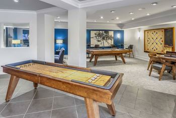 A pool table in the middle of a room with a blue wall and a painting on the wall.